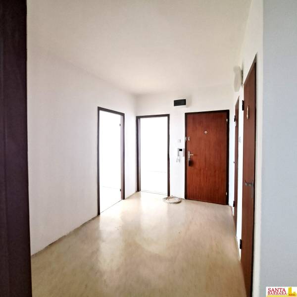 Négyszobás lakás előszobája fa mintázatú padlóval és fa ajtókkal.