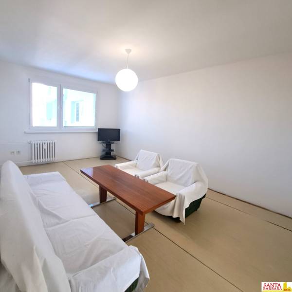 Nappali asztallal és kanapéval egy 4 szobás lakásban, fa dekorációjú padlóval.