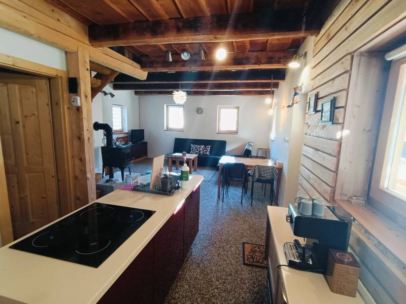 Faház fa elemekkel és cserépkályhával, fa dekorációjú padlóval, konyhaszigettel.