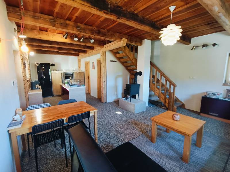 Egy fahatású padlóval, fából készült mennyezettel és cserépkályhával rendelkező házikó belső tere.