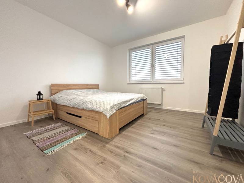 Hálószoba egy háromszobás lakásban, fa dekor padlóval és egyszerű bútorokkal.