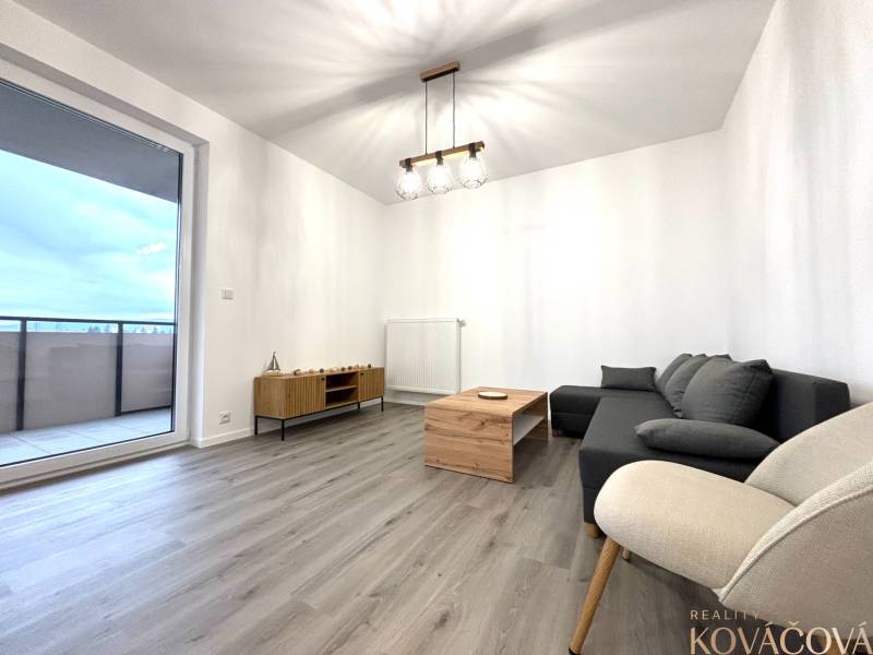 Nappali kanapéval, fotellel, asztallal és fa dekorációjú padlóval egy háromszobás lakásban.