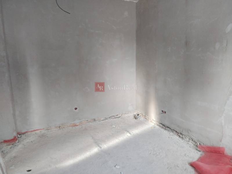 Üres belső tér vakolatlan falakkal és betonpadlóval egy családi házban.