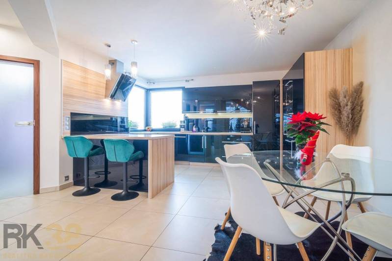 Világos konyha étkezőasztallal és bárszékekkel egy családi házban.