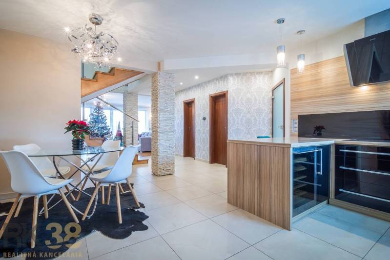 Családi ház belső tere étkezőasztallal, lépcsővel és karácsonyfával.