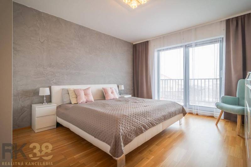 Hálószoba családi házban ággyal, éjjeliszekrényekkel és fa dekoros padlóval.