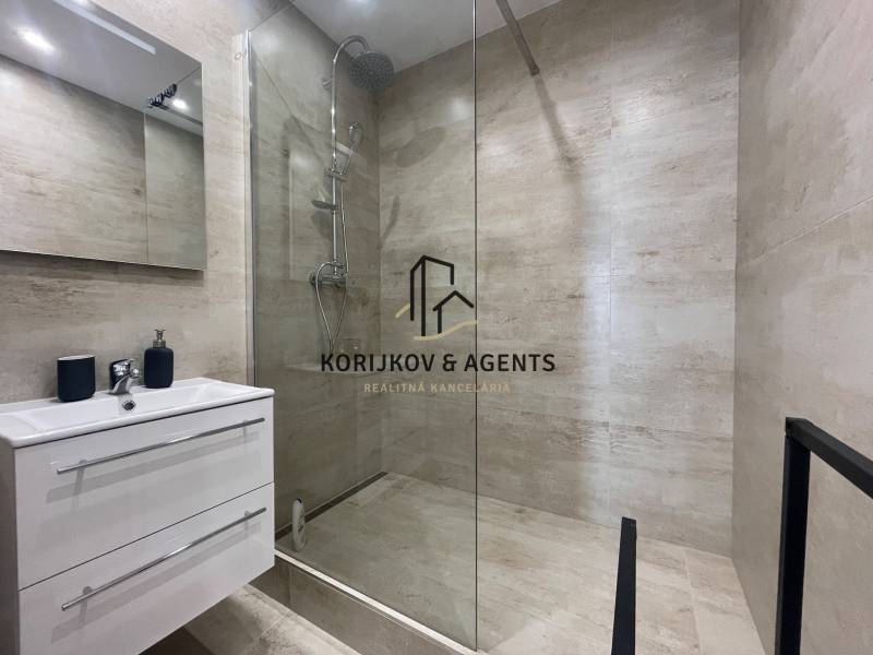 Fürdőszoba háromszobás lakásban zuhanyzóval és mosdó alatti tárolóhellyel.