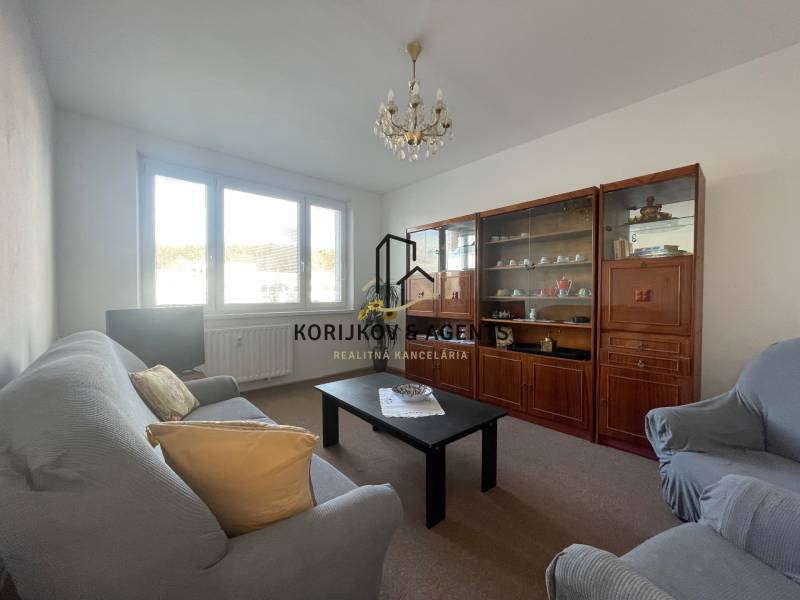 Obývací szoba egy háromszobás lakásban kanapéval, fotelekkel és nappali szekrénnyel.