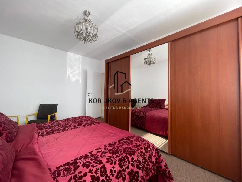 Hálószoba nagy szekrénnyel, csillárral és ággyal egy háromszobás lakásban.