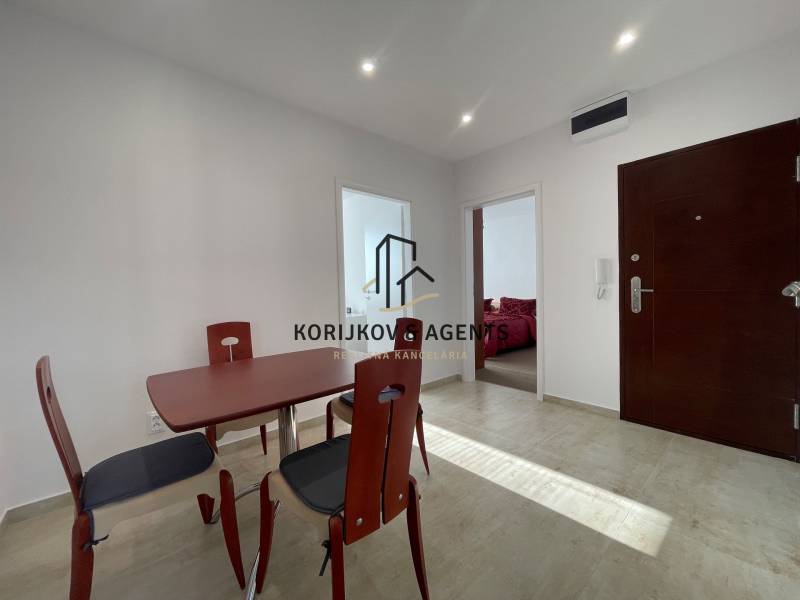 Ebédlőasztal és székek a háromszobás lakás előszobájában, járólappal.