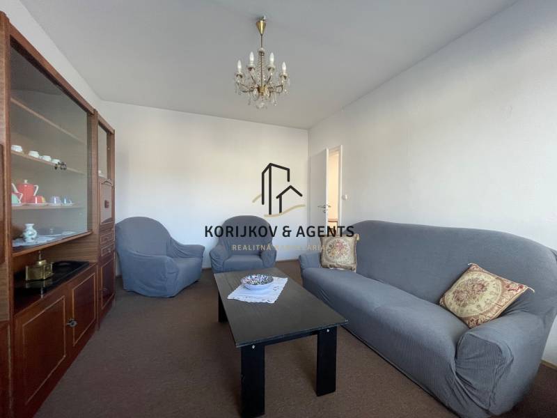 Nappali egy háromszobás lakásban kényelmes kanapéval, fotelekkel és vitrinnel.