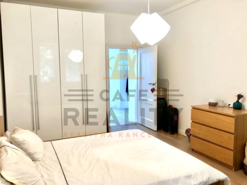 Hálószoba egy kétszobás lakásban fehér szekrénnyel, ággyal és komóddal.