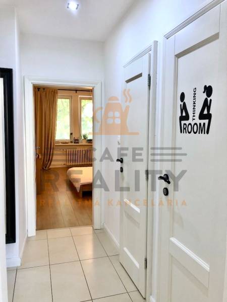 Folyosó egy kétszobás lakásban fehér falakkal és csempével.