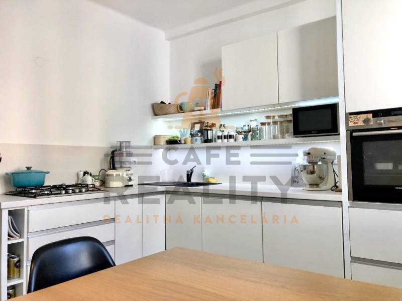 Konyha egy kétszobás lakásban fehér szekrényekkel és beépített készülékekkel.