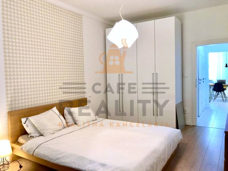 Hálószoba egy kétszobás lakásban fehér szekrénnyel és fa mintázatú padlóval.