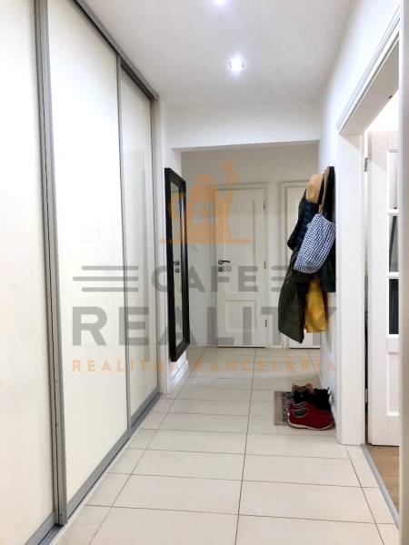 Folyosó csempével és szekrénnyel egy kétszobás lakásban, ruhafogasokkal.