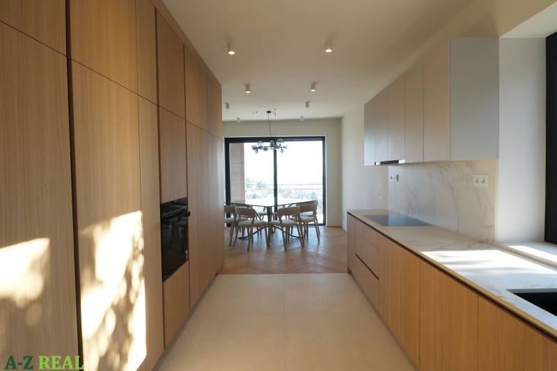 Konyha egy 4 szobás lakásban, fa dekoros padlóval és világos konyhabútorral.