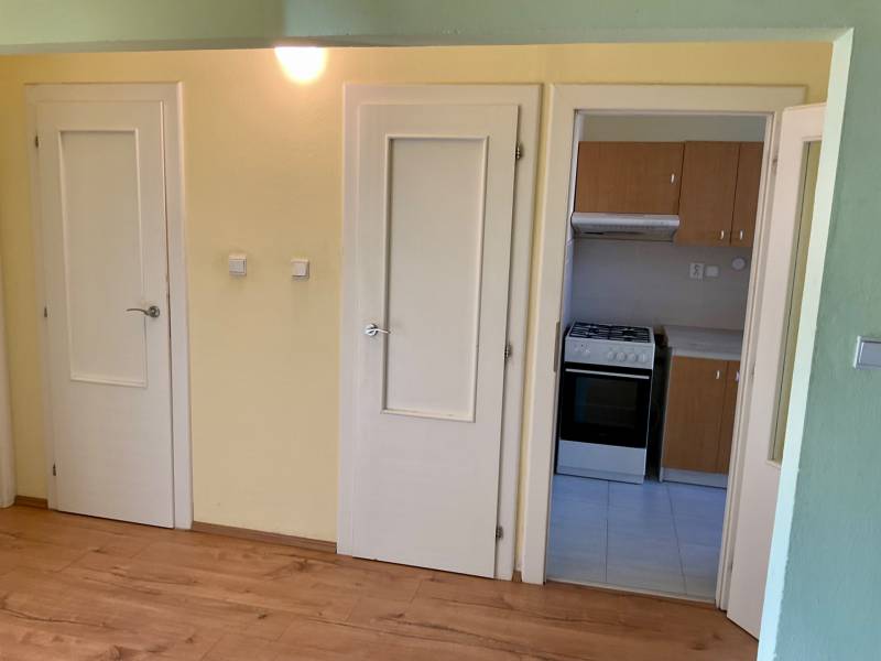 3 szobás lakás belső tere fa dekor padlóval és konyhabútorral.