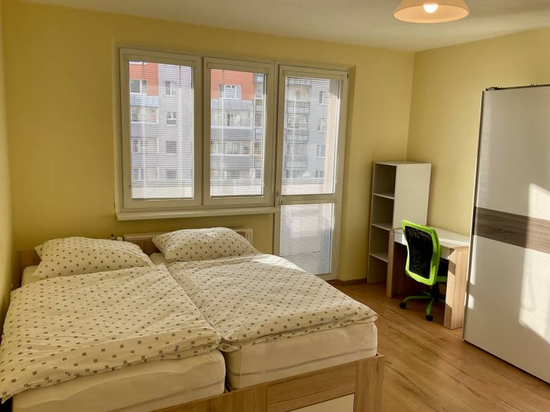 Hálószoba franciaággyal, íróasztallal és fa dekorációjú padlóval egy háromszobás lakásban.