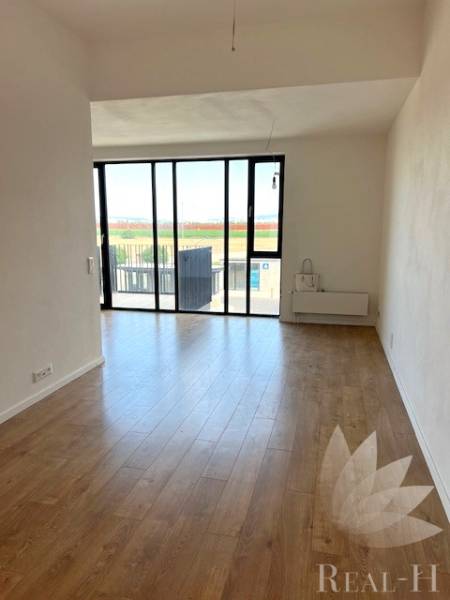 Világos nappali nagy ablakokkal és fa mintázatú padlóval egy kétszobás lakásban.