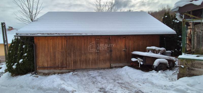 Az Ochodnicéből származó fényképen egy családi ház melletti, hóval borított fa tárolóépület látható.