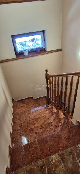 Családi ház lépcsője kerámia burkolattal és fa korláttal.