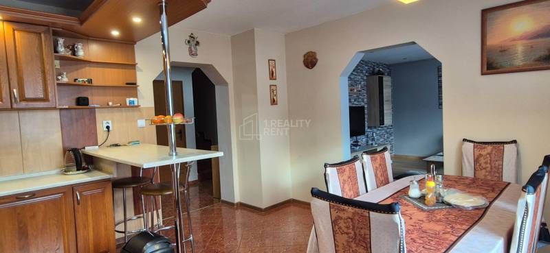 Ebédlő egy családi házban fa elemekkel, asztallal és székekkel, világos belső tér.