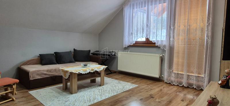 Nappali egy családi házban kanapéval, asztallal, szőnyeggel és fa dekorációjú padlóval.