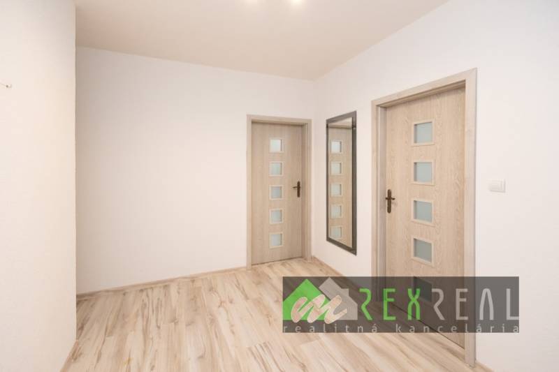 Előszoba egy háromszobás lakásban fa dekoros padlóval és tükörrel.