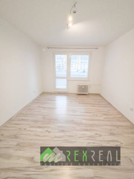 Világos szoba fa mintázatú padlóval egy háromszobás lakásban.