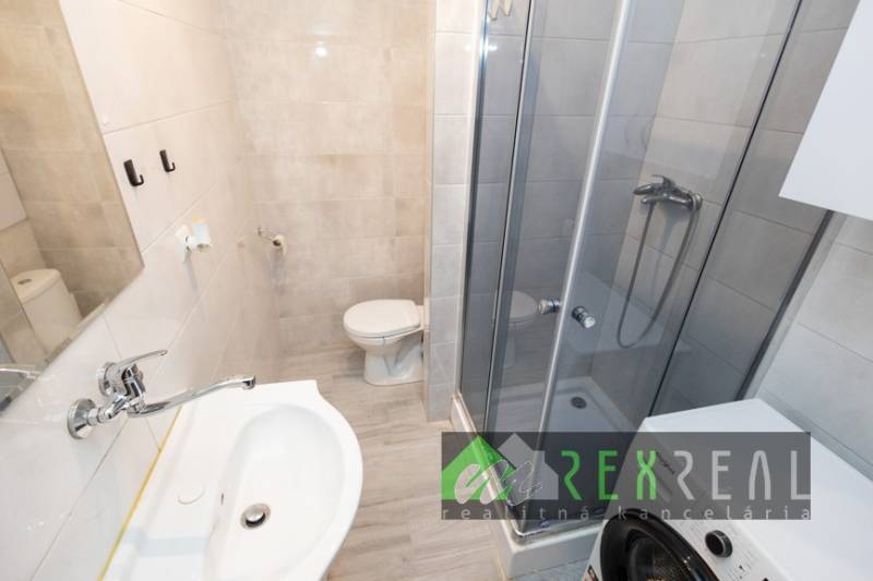 Fürdőszoba egy háromszobás lakásban mosdóval, zuhanyzóval és mosógéppel.