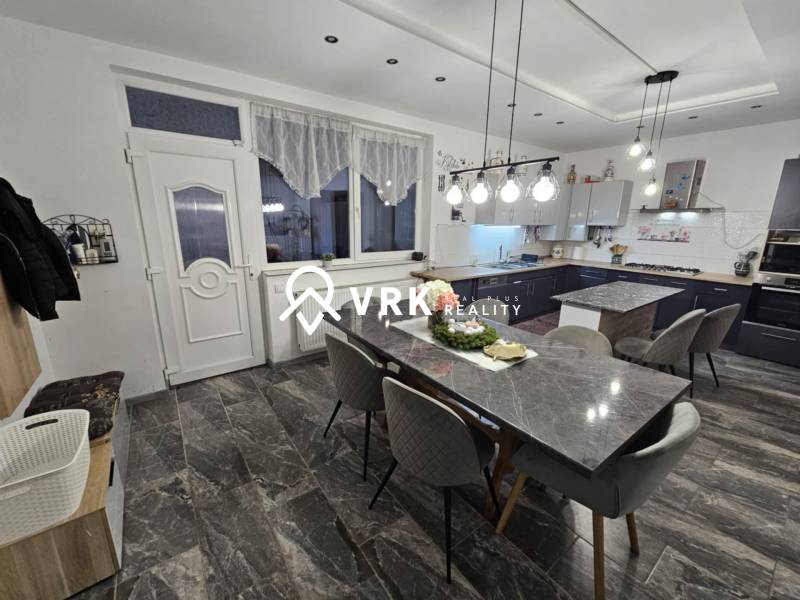 Étkező tér kőasztallal, szürke székekkel és függő lámpákkal egy családi házban.