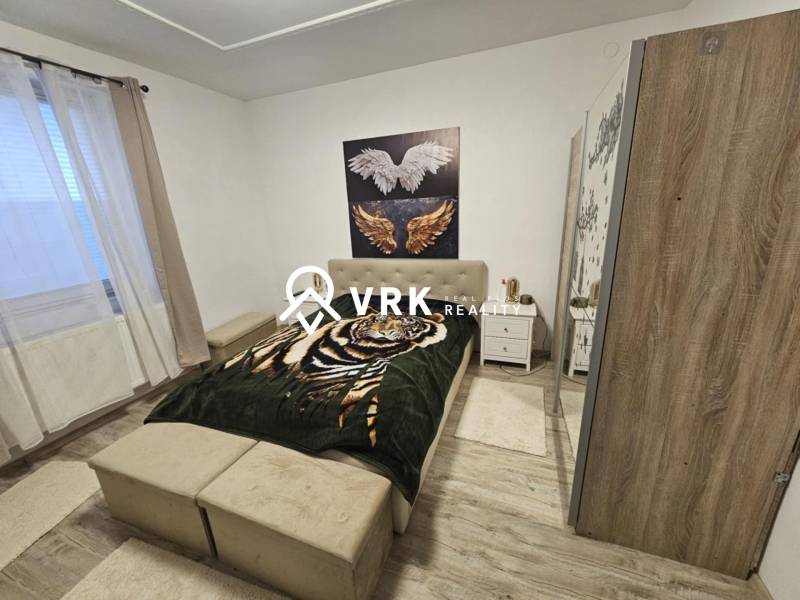 Hálószoba ággyal, szekrénnyel és fa dekorációjú padlóval egy családi házban.