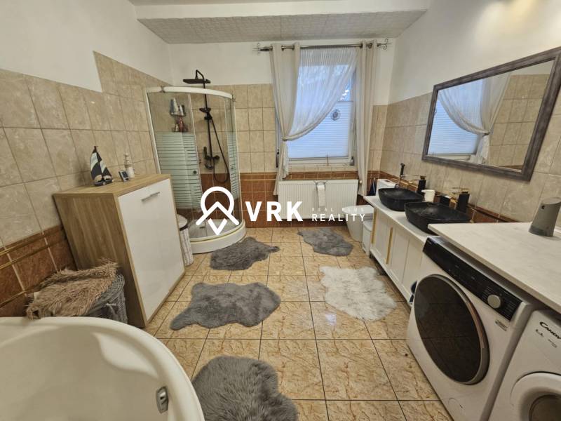 Fürdőszoba családi házban káddal, zuhanyzóval és mosógéppel.