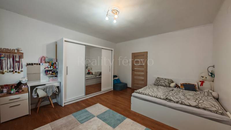 Gyerekszoba ággyal, szekrénnyel, íróasztallal és fa dekoros padlóval egy családi házban.