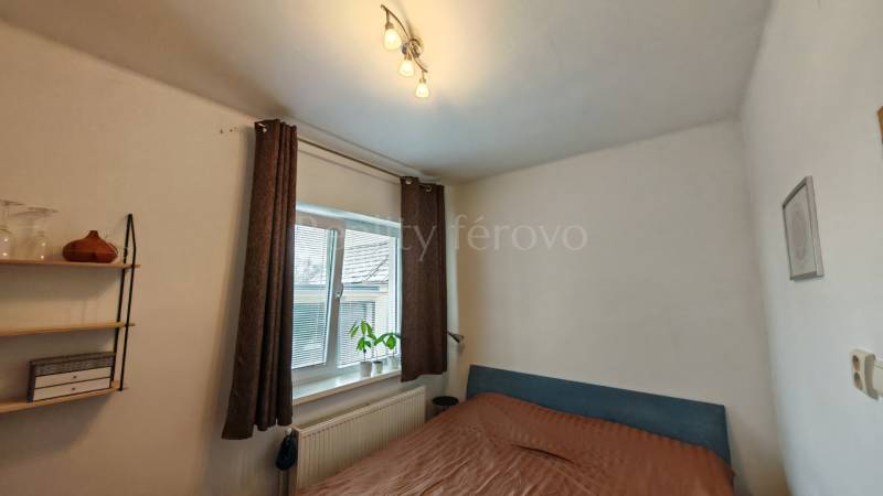 Hálószoba családi házban, ággyal, polcokkal és ablakkal, dekoratív növénnyel.