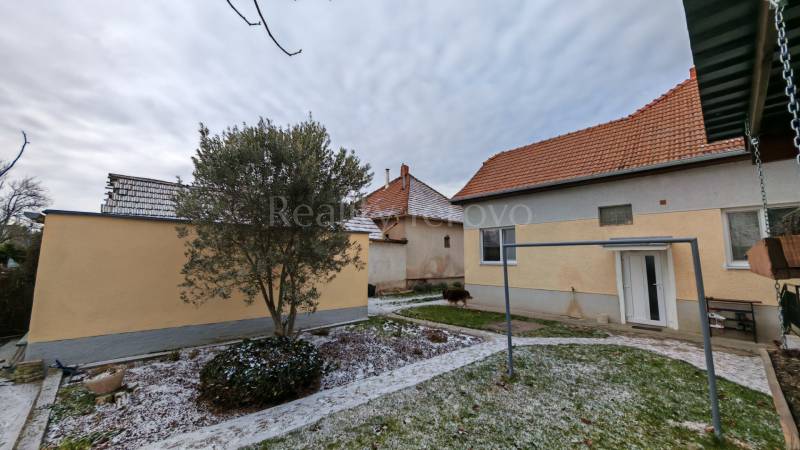 Havas kert családi házzal Trnovec nad Váhom-ban, fákkal és gyepes területtel körülvéve.