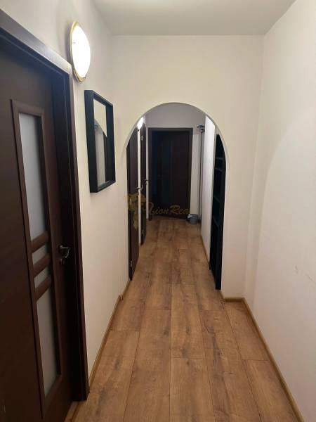 Keskeny folyosó egy kétszobás lakásban, fa mintázatú padlóval és sötét ajtókkal.