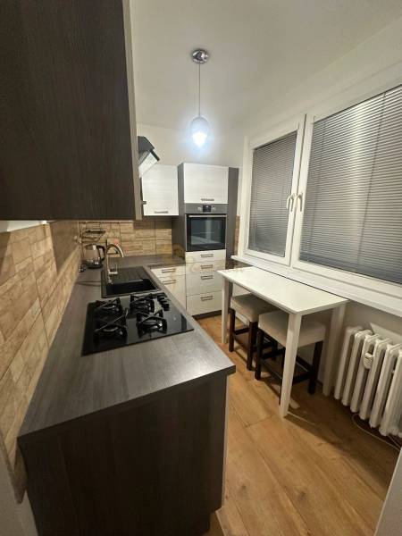 Konyha egy kétszobás lakásban, fa dekorációjú padlóval és gáz tűzhellyel.