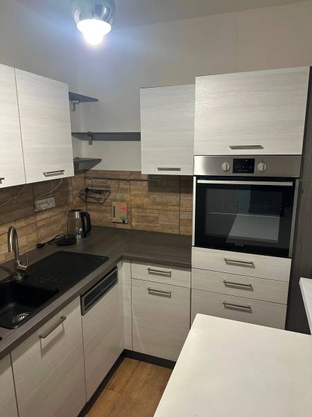 Konyha egy kétszobás lakásban, fa dekoros padlóval és beépített sütővel.