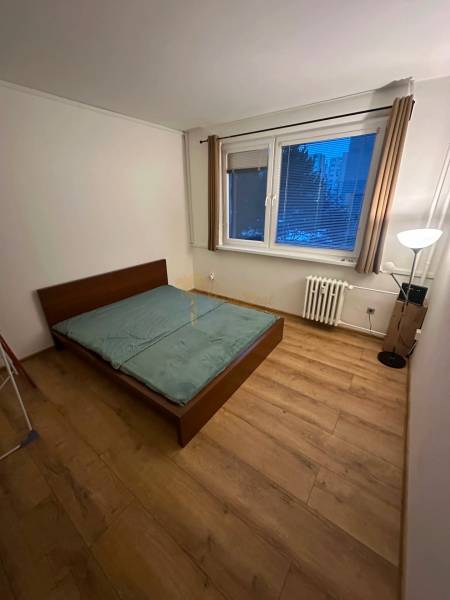 Hálószoba egy kétszobás lakásban, ággyal és fa dekor padlóval.