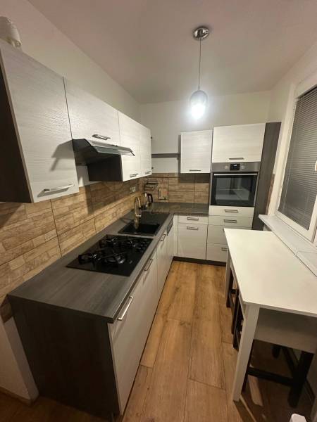 Konyha egy kétszobás lakásban, fa dekoros padlóval és téglafalakkal.