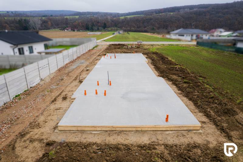 Egy családi ház alapjai Sokolovcén, vidéki tájjal és szomszédos házakkal körülvéve.