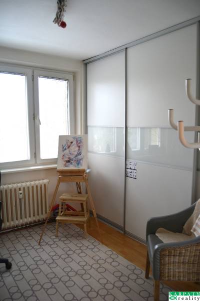 Egyszerű belső tér egy háromszobás lakásban, székkel, asztalkával és szekrénnyel.