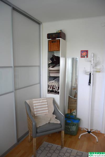 Kényelmes fotel fa dekorációjú padlóval egy háromszobás lakásban.