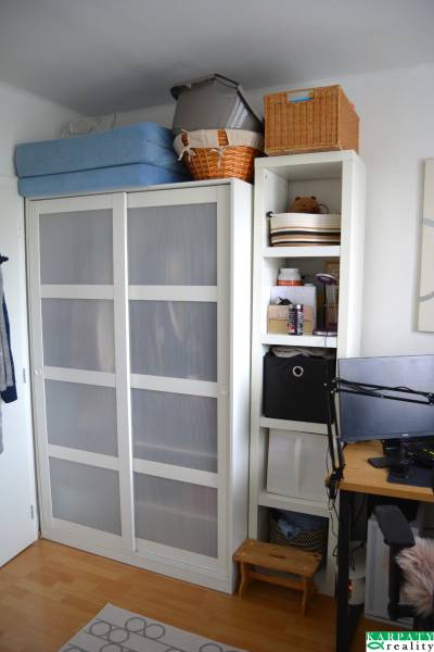 3 szobás lakás belső tere fehér szekrénnyel és polcokkal, fa dekoros padlóval.