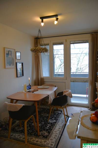 Étkező sarok egy háromszobás lakásban szőnyegmintával és üvegezett ajtókkal az erkélyre.