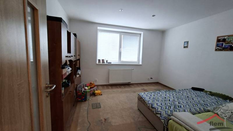 Szoba családi házban ággyal, bútorokkal és fa dekorációjú padlóval.