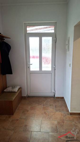 Családi ház belső tere üvegajtókkal és fa mintázatú padlóval.