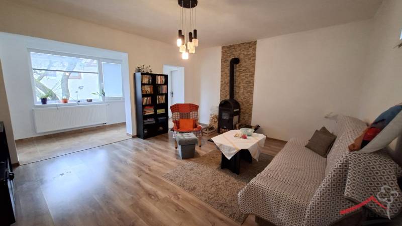 Szoba családi házban kandallóval, kanapéval, könyvtárral és fa dekorációjú padlóval.